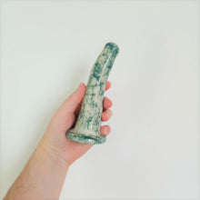 Load image into Gallery viewer, A hand holds a 6 inch curved ceramic dildo in a dark green bubble pattern in front of a white background.