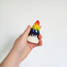 Load image into Gallery viewer, A hand holds a 3 inch cone shaped ceramic butt plug in a rainbow drip pattern in front of a white background.