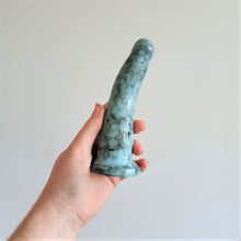 Load image into Gallery viewer, A hand holds a 6 inch curved ceramic dildo in light blue with a black bubble pattern in front of a white background.

